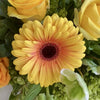 A floral arrangement with vibrant colors, green, orange, yellow, a citric explosion of colors. some lemons and limes on a plate next to the arrangement