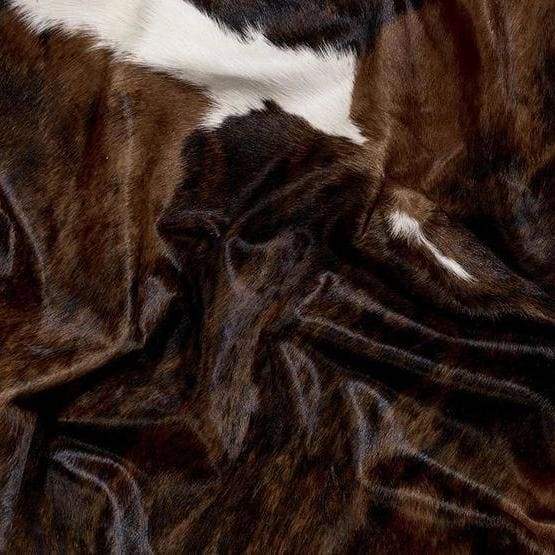A Cowhide Rug in a Dark Tricolor Pattern, including, white and dark brown and black