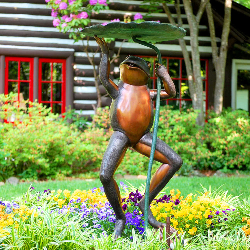 Bronze Fountain in a bed of flowers which stands in front of a rustic home 